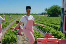 Love berries spokeswoman in pink overalls, on the strawberry farm.